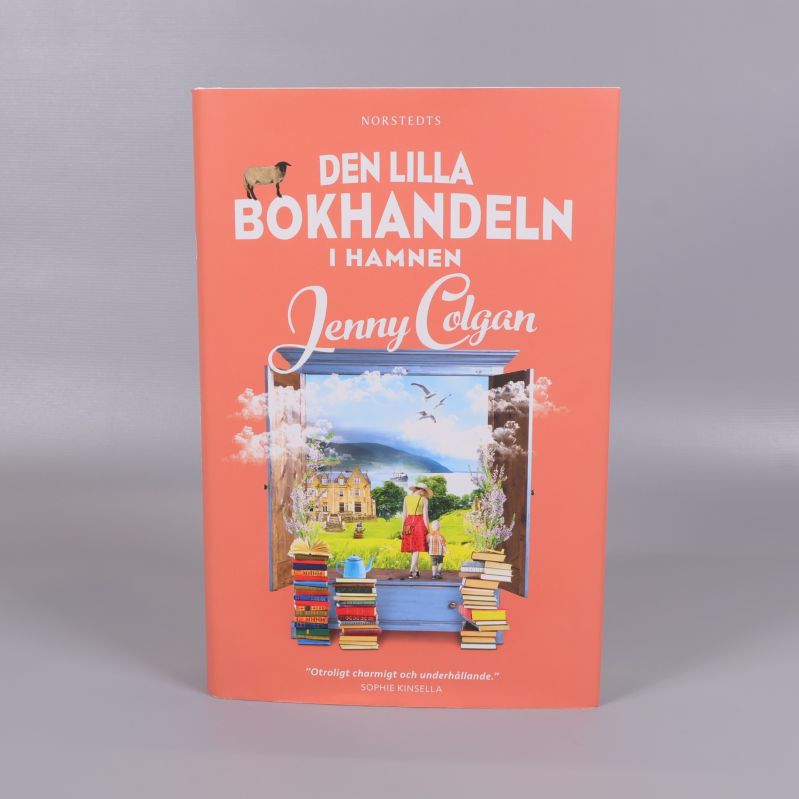 Framsidan av boken Den lilla bokhandeln i hamnen med illustrerat fönster och böcker