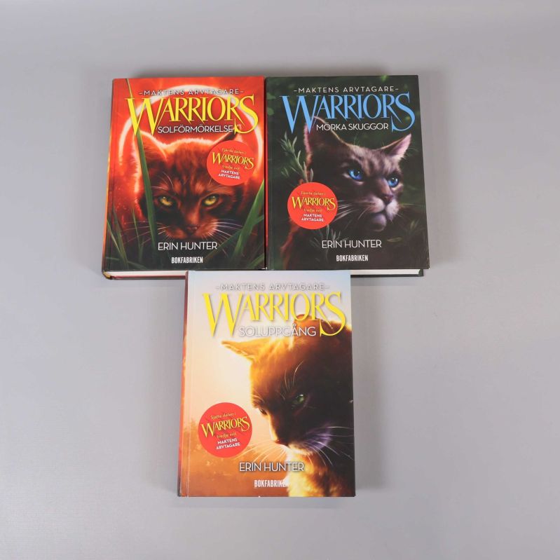 Tre inbundna Warriors-böcker med färgstarka kattmotiv på omslagen