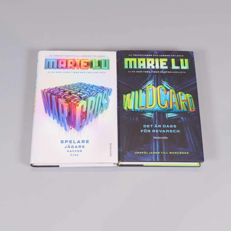 Två böcker, Warcross och Wildcard av Marie Lu, placerade sida vid sida med färgstarka omslag