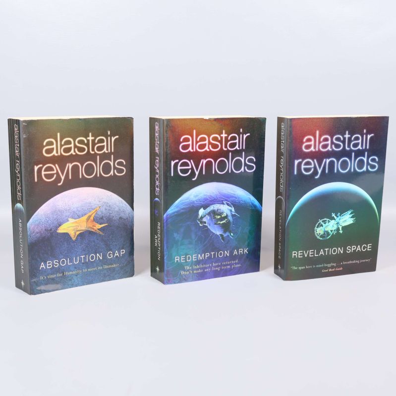 Tre stående böcker av Alastair Reynolds med färgstarka omslag