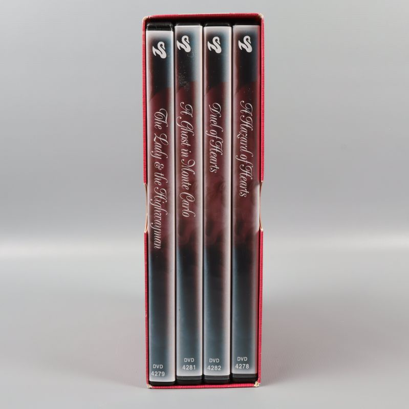 Ryggarna av fyra DVD-fodral i en röd Barbara Cartland-box