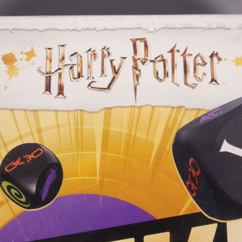Närbild på Harry Potter-logotyp och tärning med magiska symboler