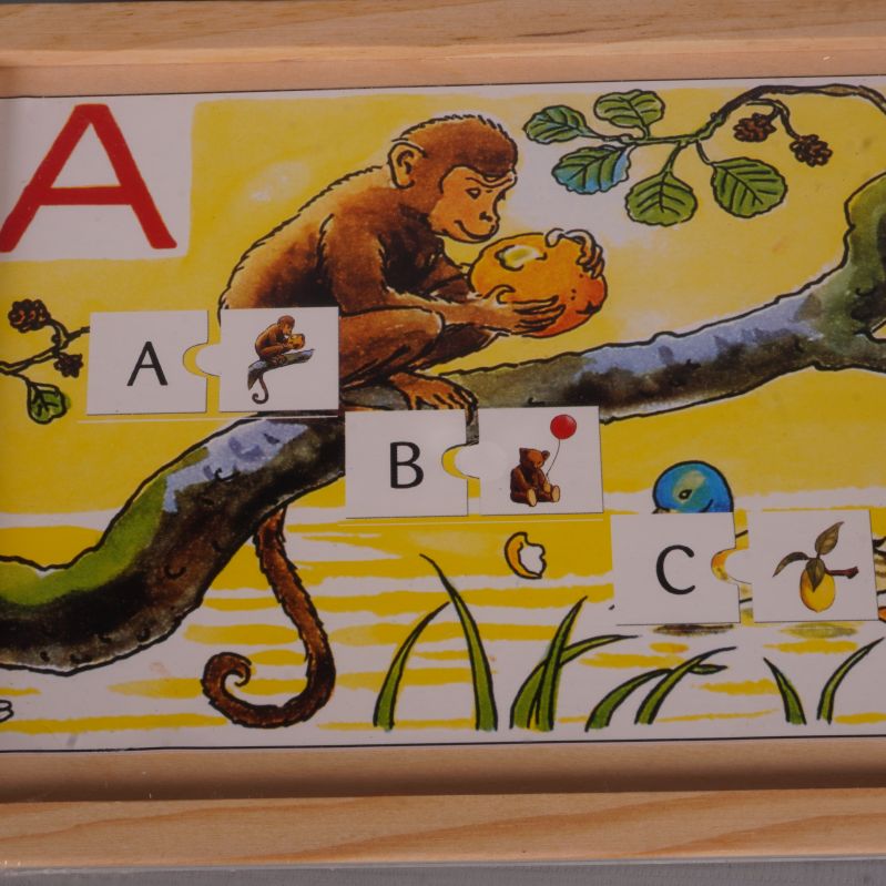 Närbild på apmotiv och pusselbitar med bokstäver på alfabetspusslet