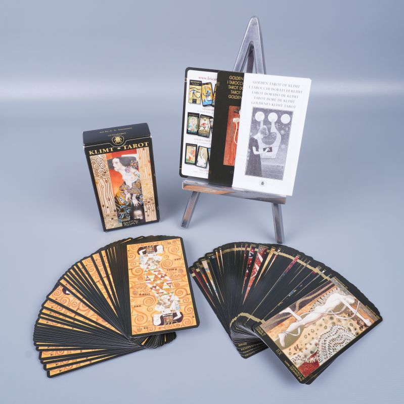 Tarotkort med ask, häfte och uppslagna kort med illustrerade motiv