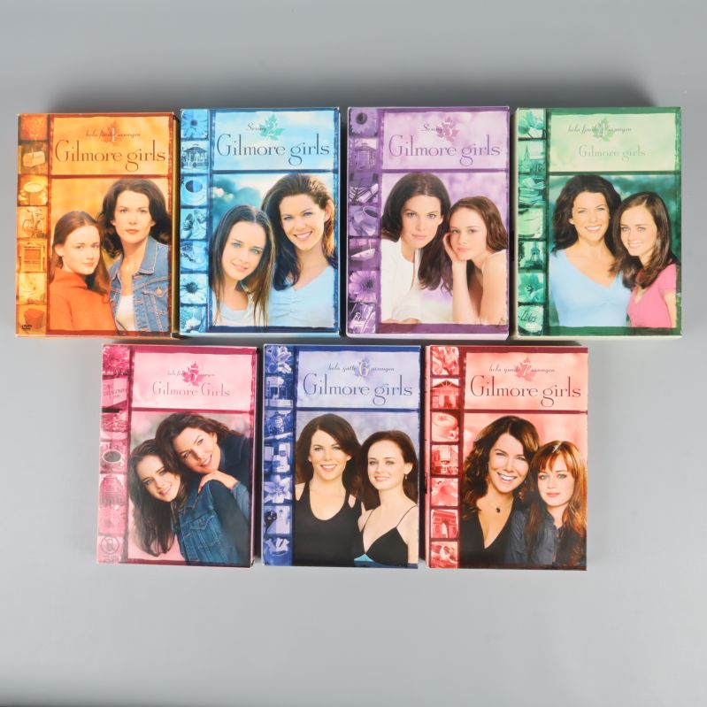 Sju DVD-boxar av Gilmore Girls säsong 1 till 7 uppställda mot grå bakgrund