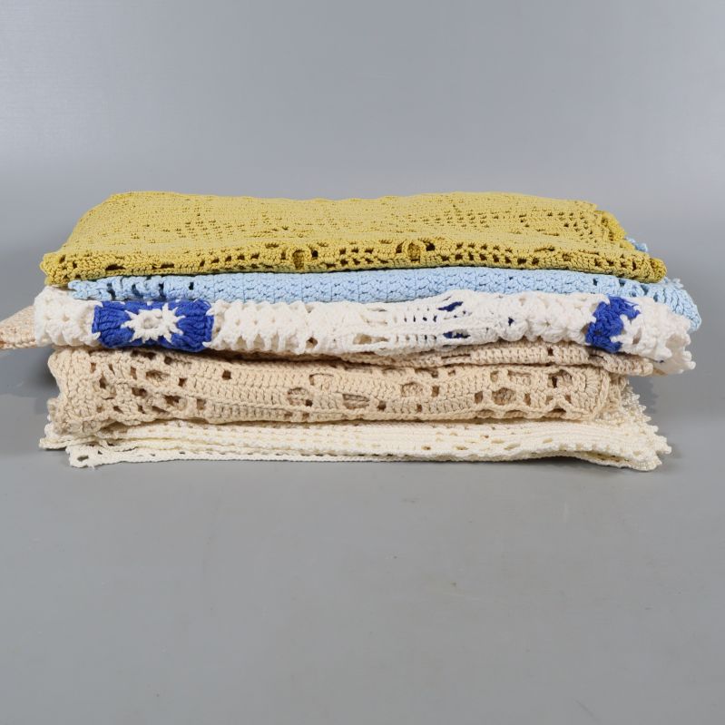 Flera vikta virkade dukar staplade på varandra i olika färger