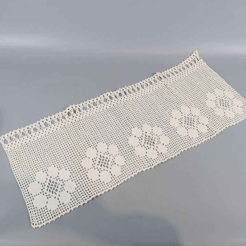 Avlång vitvirkad duk med blommotiv utlagd