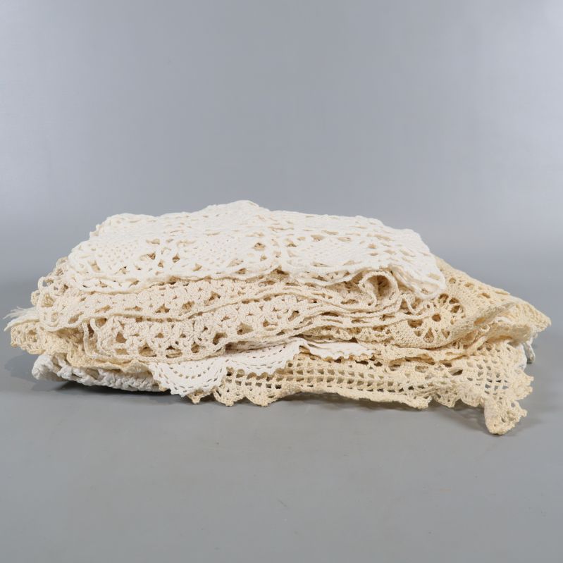 Sammansatt hög av beige och vita virkade dukar