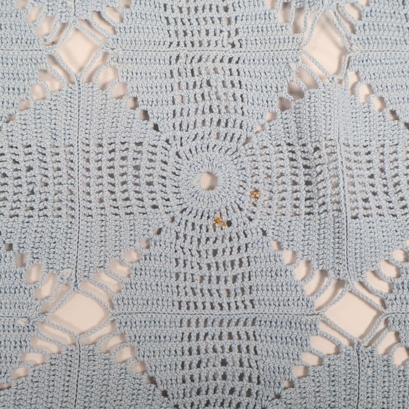 Närbild på ljusblå virkad duk med detaljerat mönster