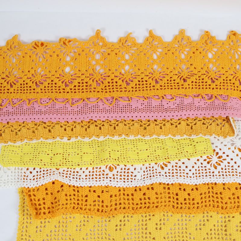Närbild på virkade spetsar i gult, rosa och vitt