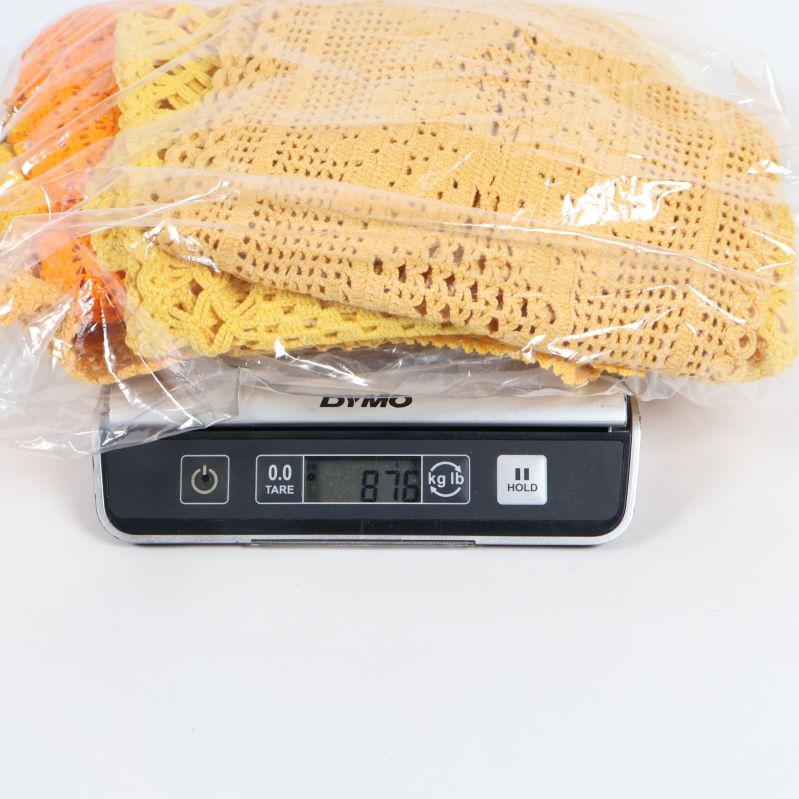 Virkade dukar i plastpåse på en våg som visar 876g