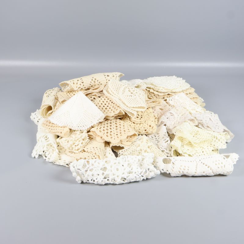 Stapel med virkade spetsdukar i olika nyanser på grå bakgrund