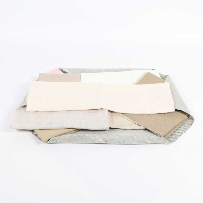 Flera tygbitar i beige och grå toner liggande på hög