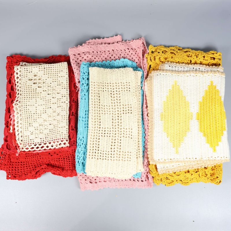 Flera vikta virkade dukar i olika färger och mönster