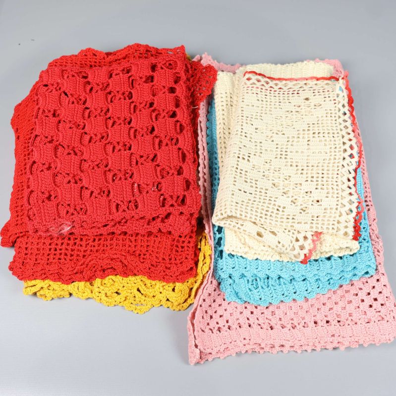 Virkade dukar i röd, gul, rosa och blå nyans staplade tillsammans