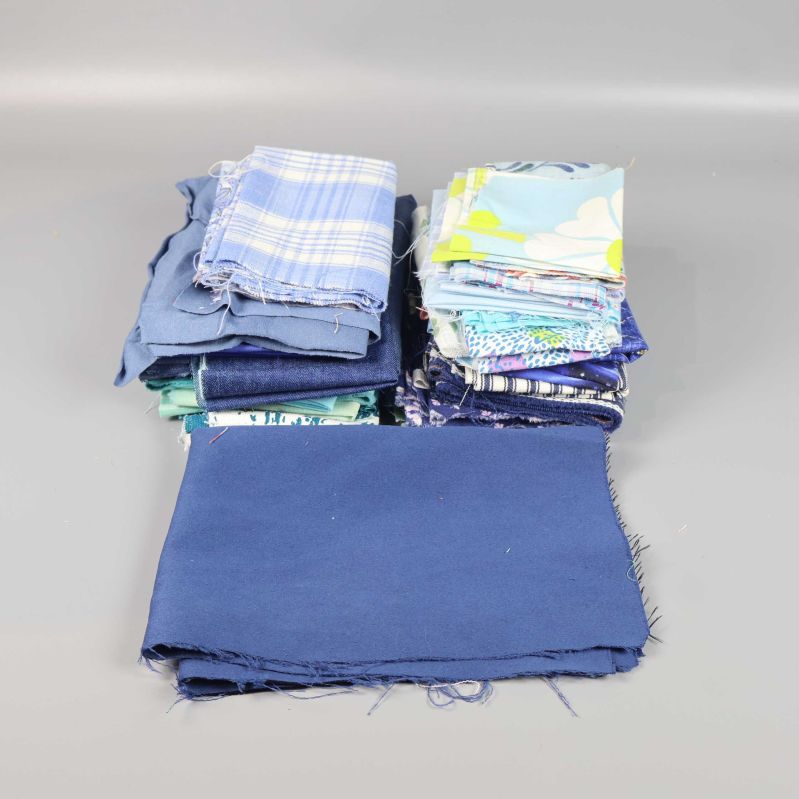 Trav av blå och mönstrade tygbitar på grå bakgrund