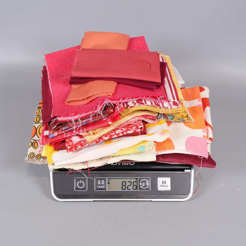 Stapel tygbitar på våg som visar 826 gram