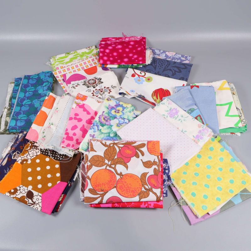 Flera tygbitar i olika mönster och färger utspridda på grå bakgrund