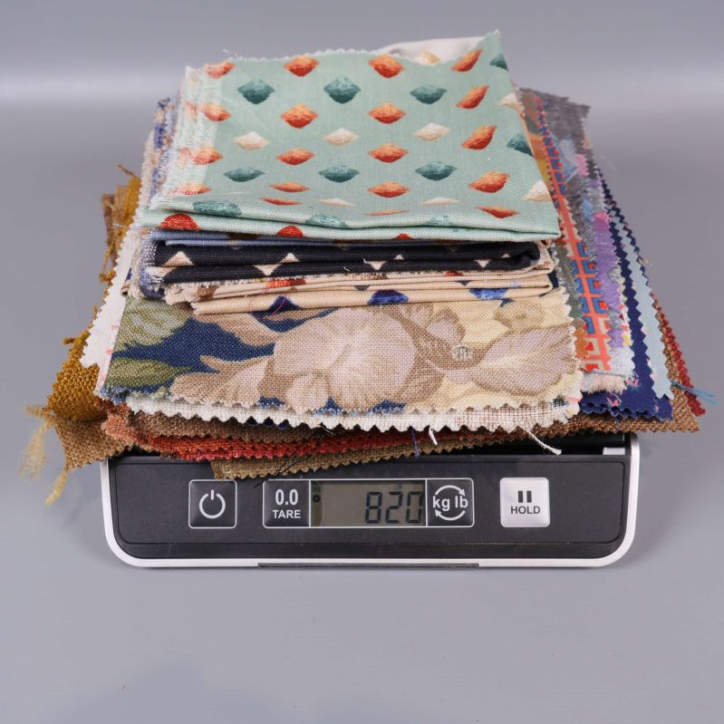 Hög med tygprover placerad på våg med totalvikt 820 gram