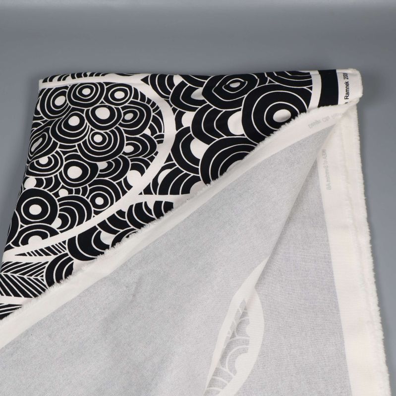 Uppvikt hörn av svartvitt mönstrat tyg på grå bakgrund