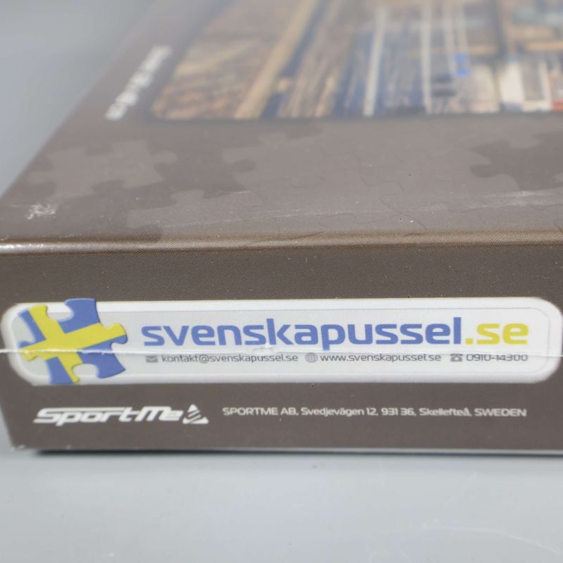 Närbild på varumärkeslogga svenskapussel.se på kartongens kortsida