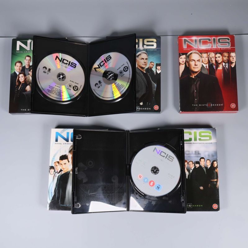Öppna DVD-fodral visar NCIS-skivor inuti boxarna