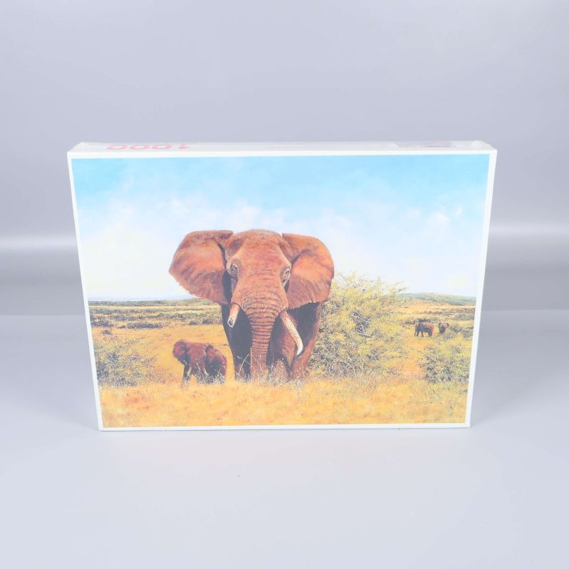 Framsidan av pussellådan visar elefanter på savannen under blå himmel
