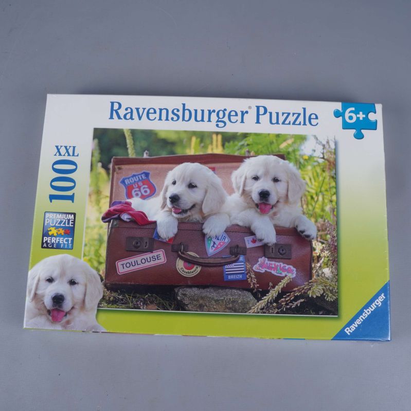 Framsidan på Ravensburger pussel med hundvalpar och resväska samt XXL och 100 bitar markerat