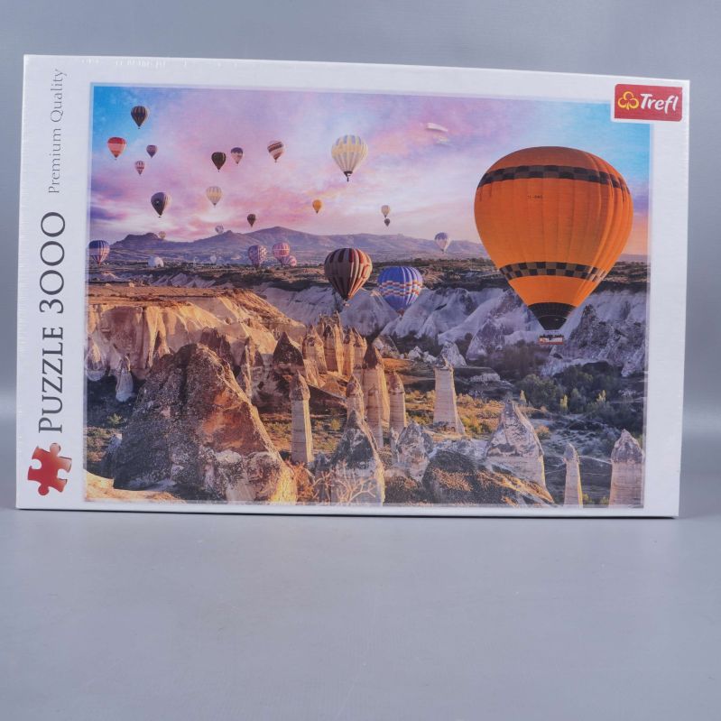 Framsidan av Trefl pussel med luftballonger över berg