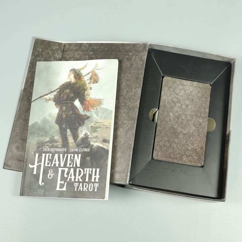 Uppslagna tarotkort och bok Heaven & Earth Tarot ovanpå yta
