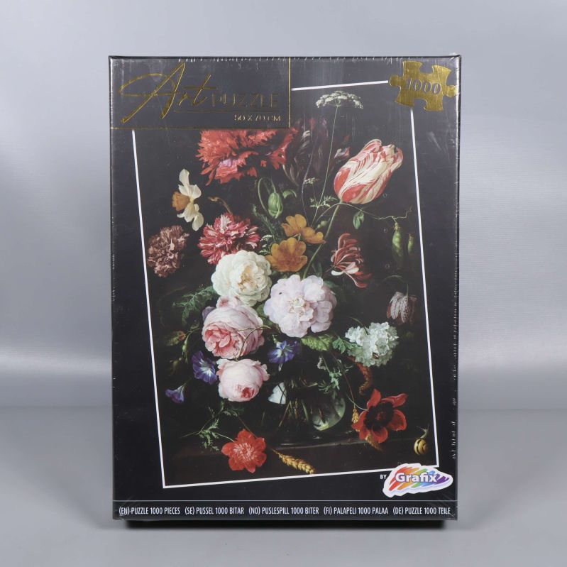 Framsidan av pussellådan med blomstermotiv och Grafix-logga