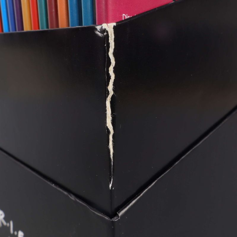 Närbild på slitage och repa vid hörn av Friends-boxen