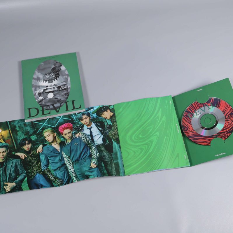 Uppvikt fotobok med gruppbild och CD-skiva synlig