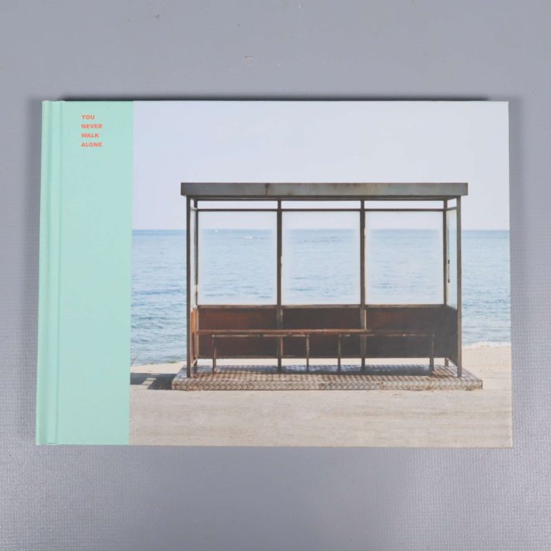 K-pop album med omslag som visar busshållplats vid havet