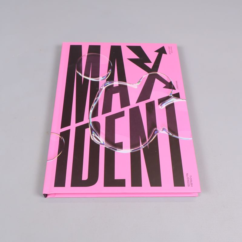 Stängd rosa fotobok med svart text MAXIDENT på framsidan