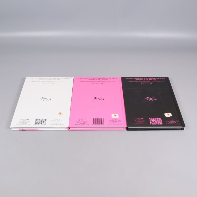 Baksidan av tre MAXIDENT-album i vitt, rosa och svart