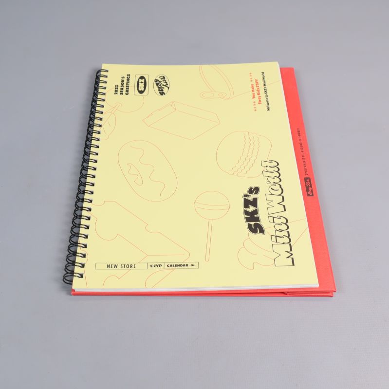 Spiralbunden kalender med gul och röd framsida samt Stray Kids illustrationer