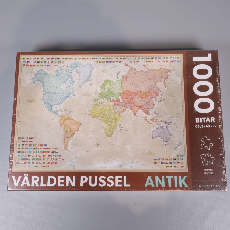 Pussellåda med antik världskarta och texten 1000 bitar