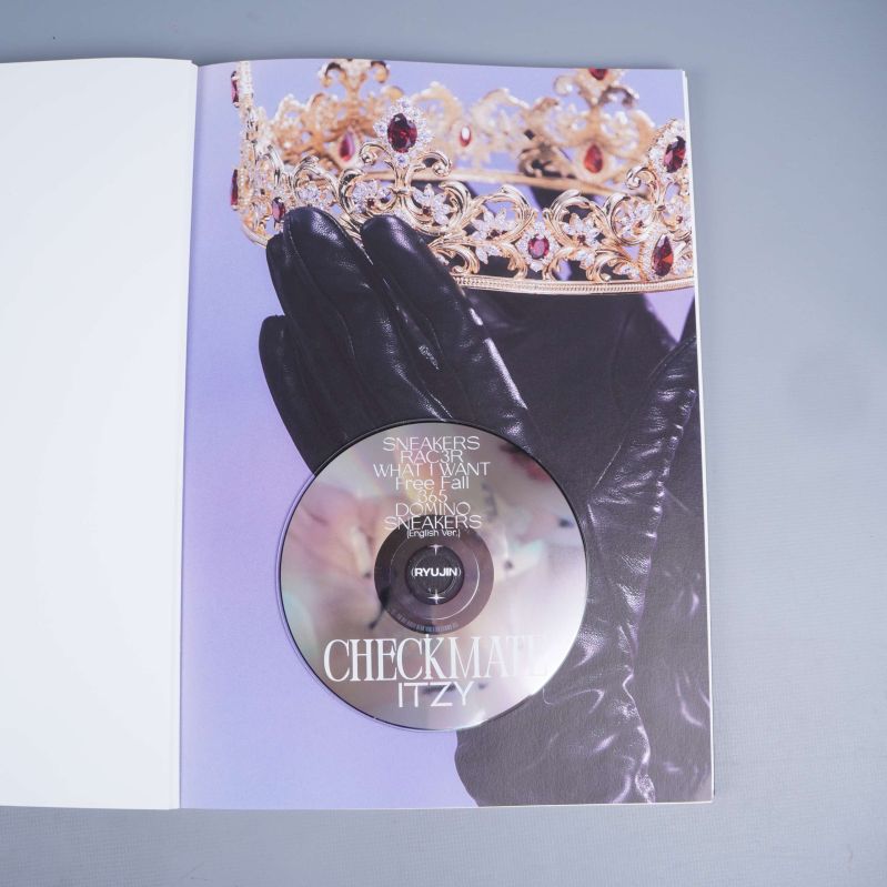 CD-skiva i fotobok med handskar och krona i bakgrund