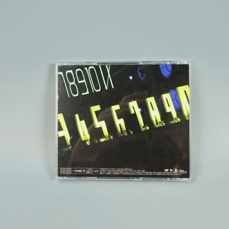 Baksidan av Perfume livealbum med svart bakgrund och neontext