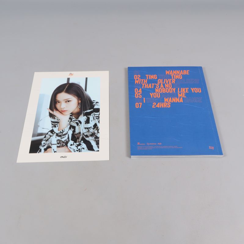 ITZY-album och fotografi av en medlem utlagda på grå yta