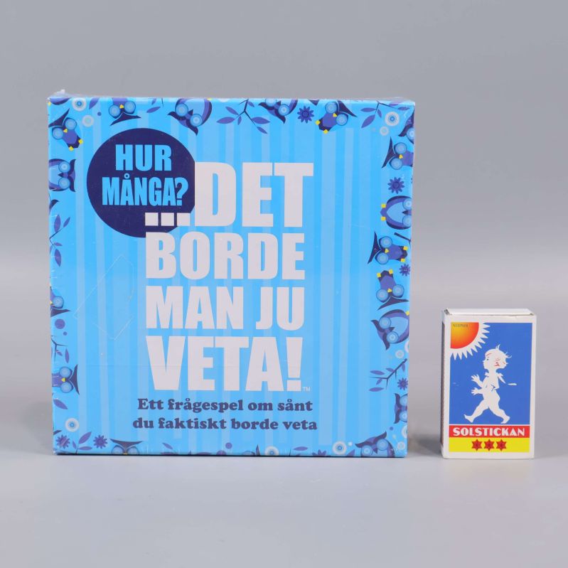 Frågespelsbox bredvid tändsticksask för storleksjämförelse