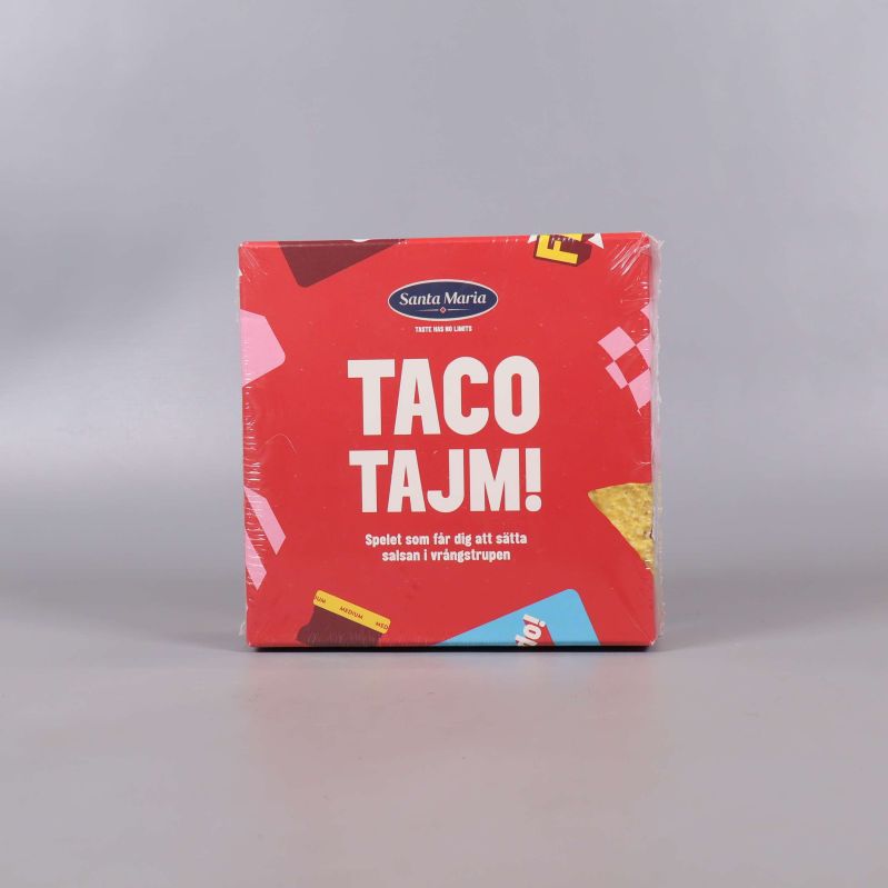 Framsidan av sällskapsspelet Taco Tajm med röd bakgrund och tacoillustration