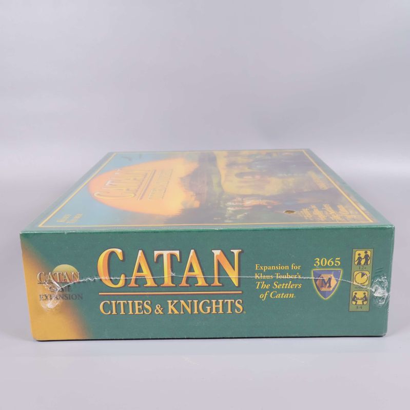 Långsidan på Catan Cities & Knights expansionslåda med titel och symboler