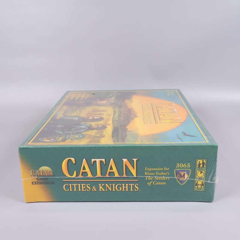 Långsida på Catan Cities & Knights expansionslåda med gul och grön design
