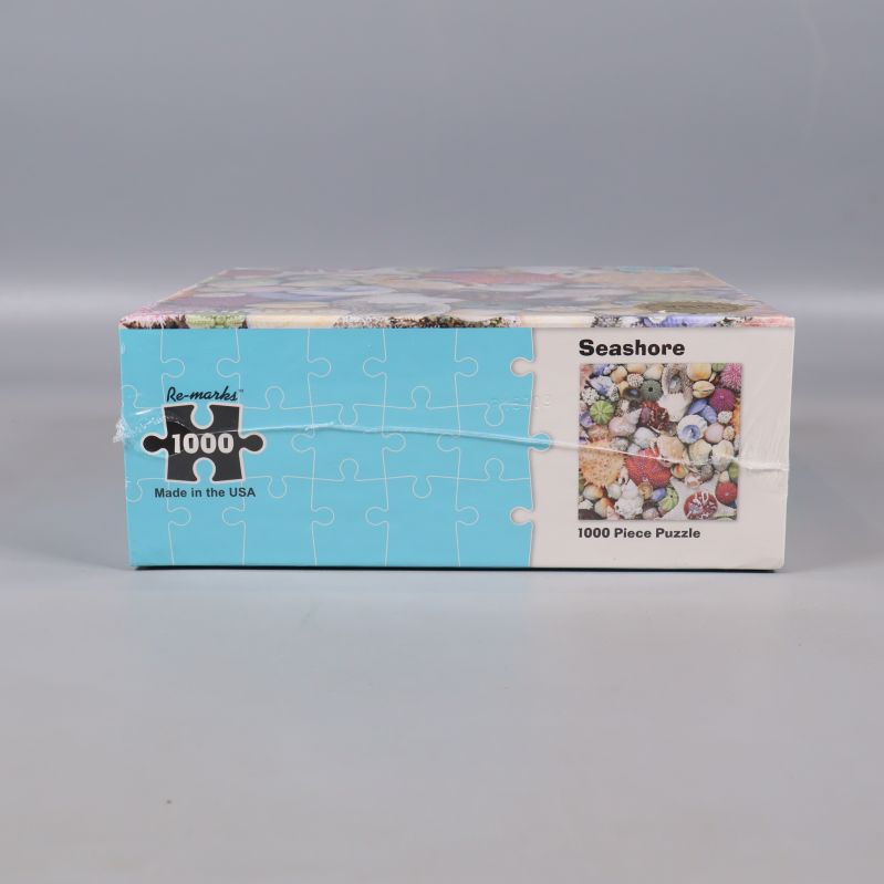 Sida av lådan med snäckmotiv, visar texten Seashore 1000 Piece Puzzle