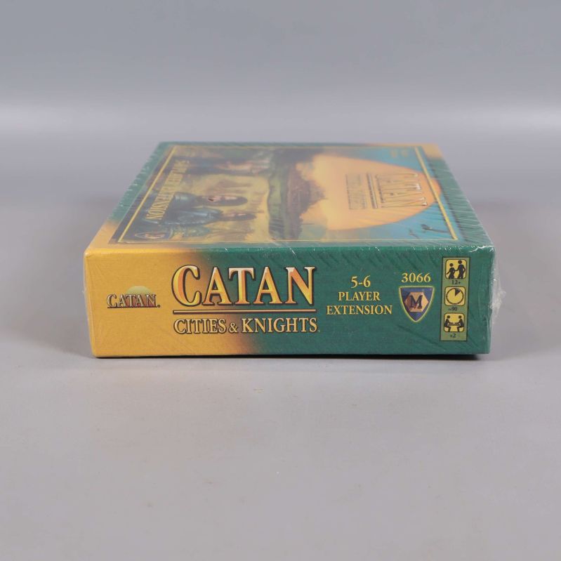 Undersidan av Catan Cities & Knights boxen med expansionstitel och symboler