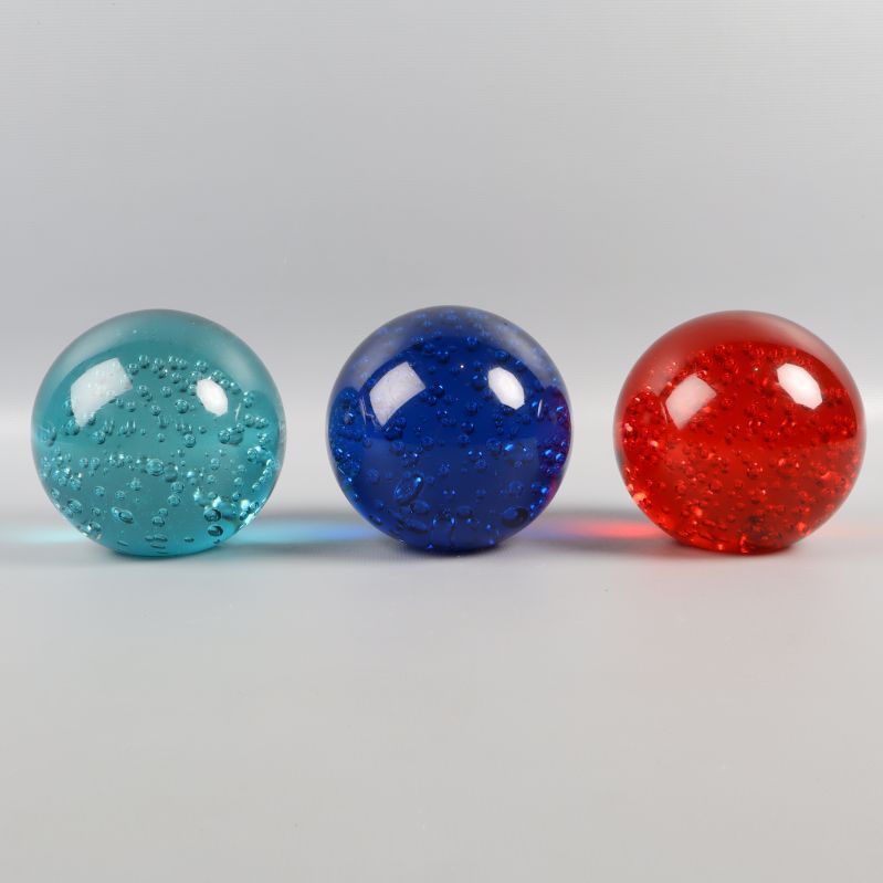 Tre glaskulor med bubblor i olika färger