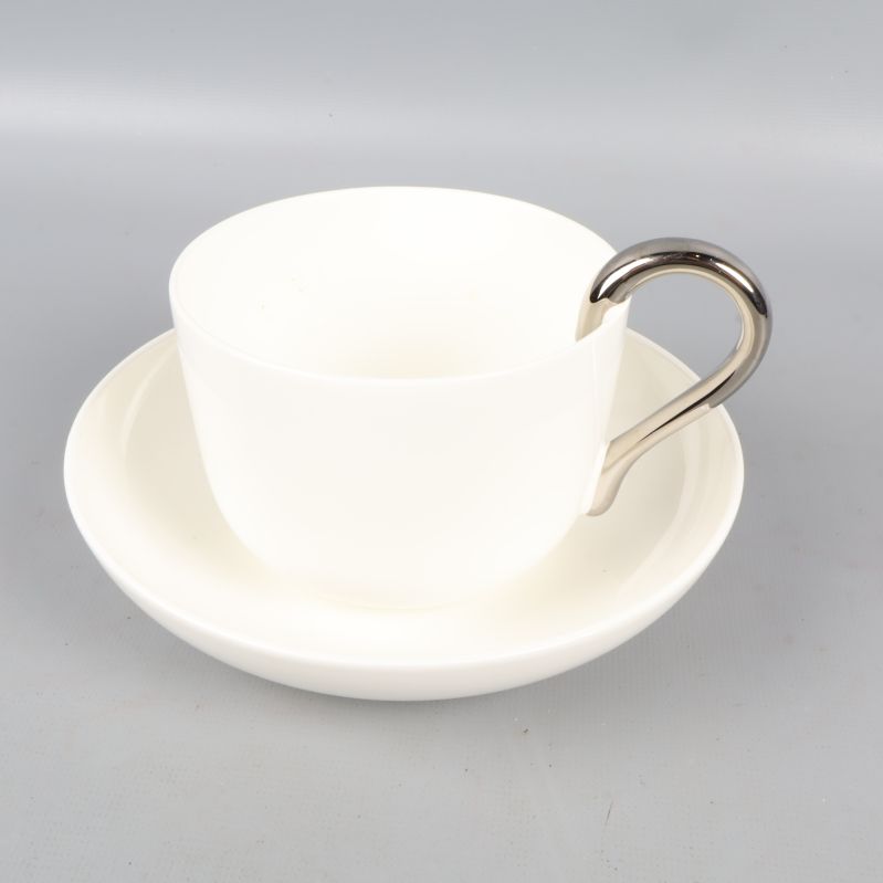 Vit kopp med silver handtag och fat