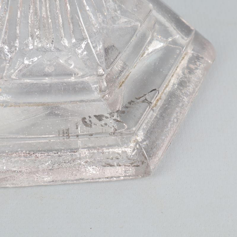 Närbild av glasskålens fot med sprickor och smuts